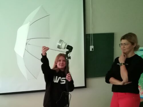 Uczennica ósmej klasy montuje parasolkę fotograficzną