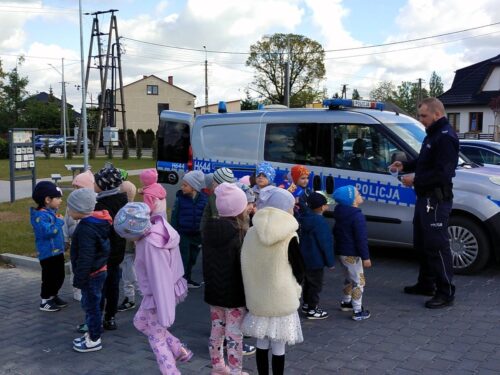 Dzieci słuchają policjanta, który opowiada o swojej pracy