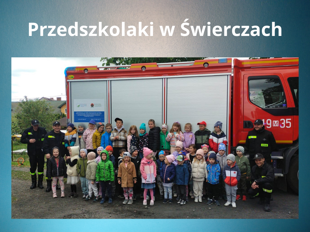 Grupa dzieci ze strażakami na tle wozu strażackiego