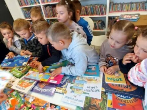 Dzieci oglądają książki w Gminnej Bibliotece w Świerczach